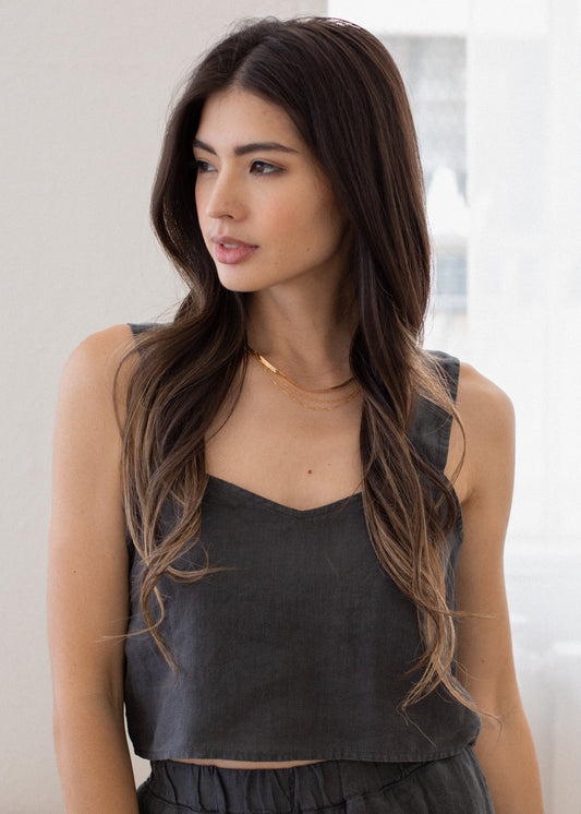 Woman wearing a dark gray tank top against a neutral background