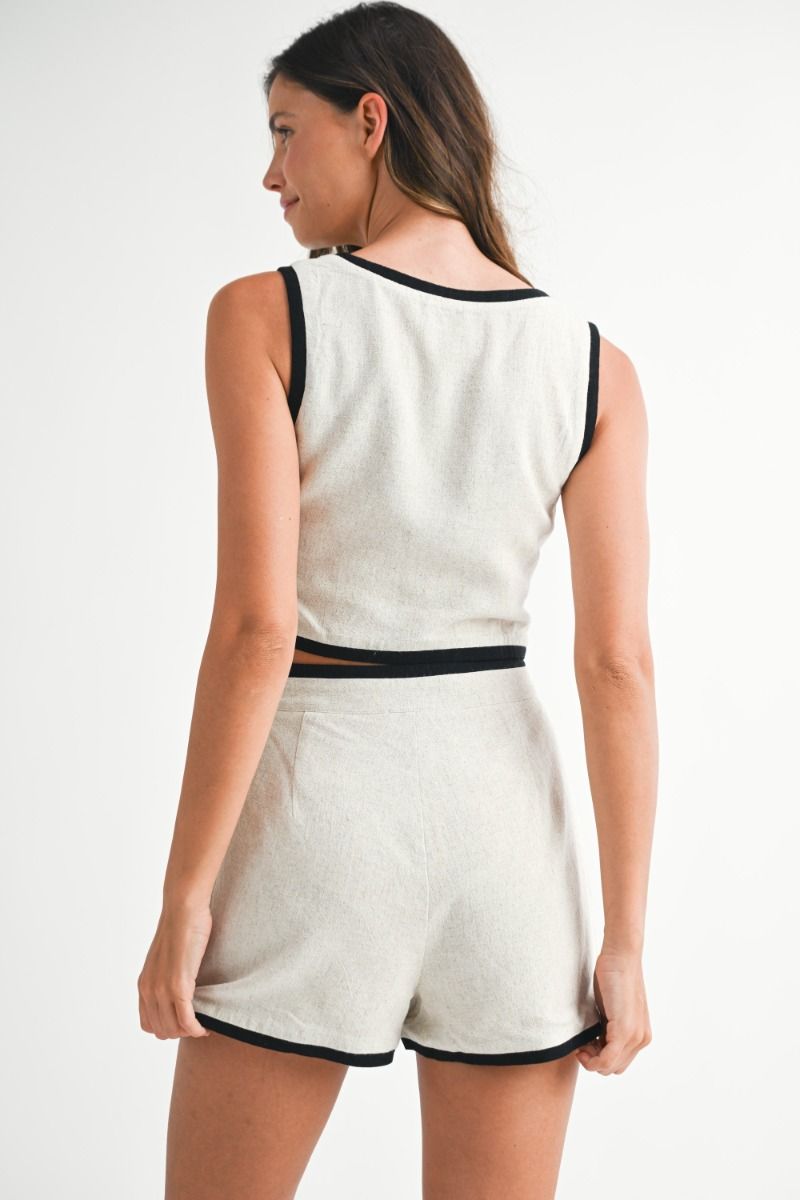 Woman wearing a white sleeveless top and shorts with black trim on a white background