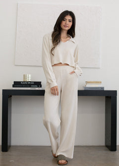 Woman in a white outfit standing in a minimalistic room with a black console table.
