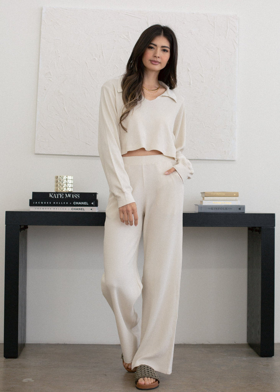 Woman in a white outfit standing in a minimalistic room with a black console table.