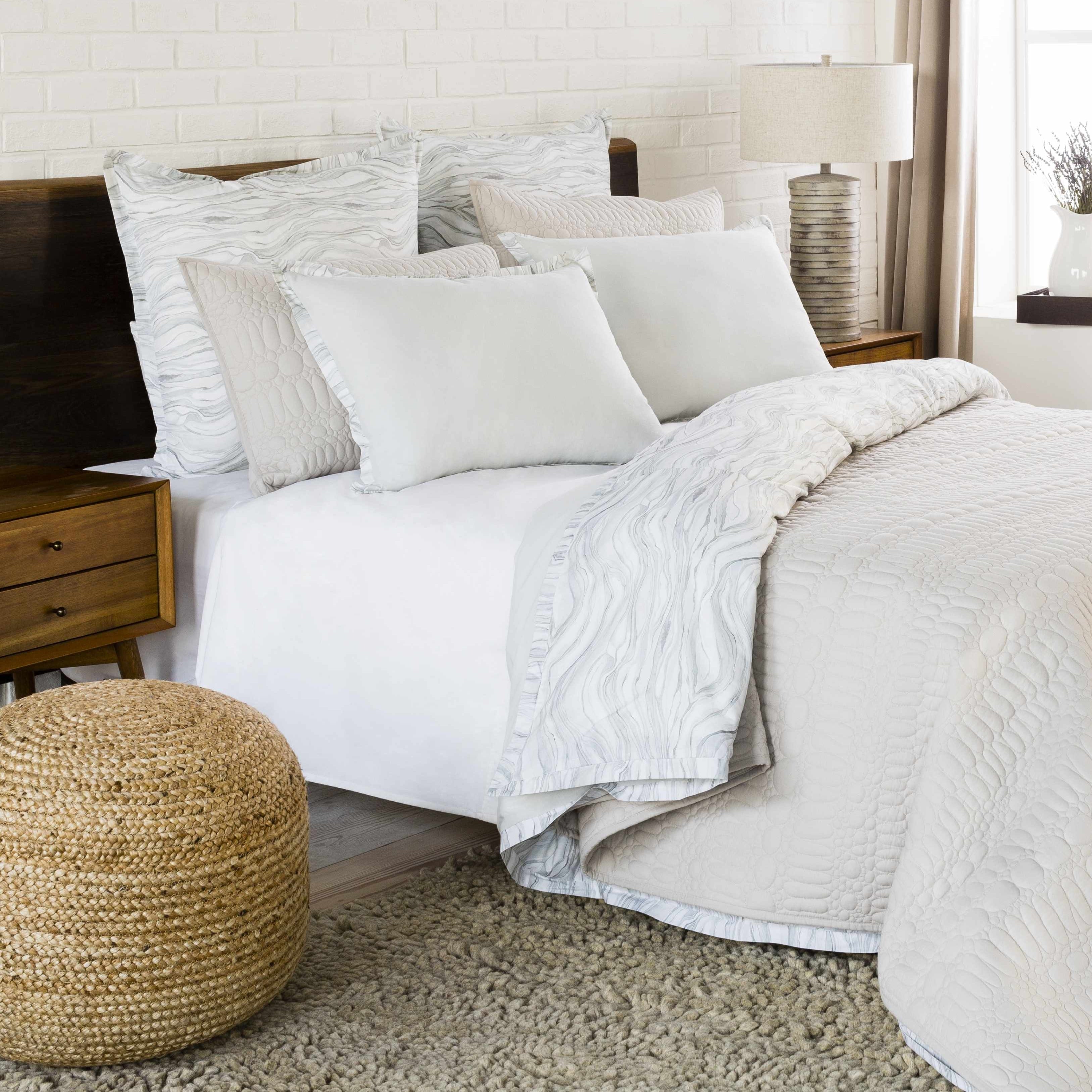 Neatly made bed with white bedding and pillows in a bedroom setting.
