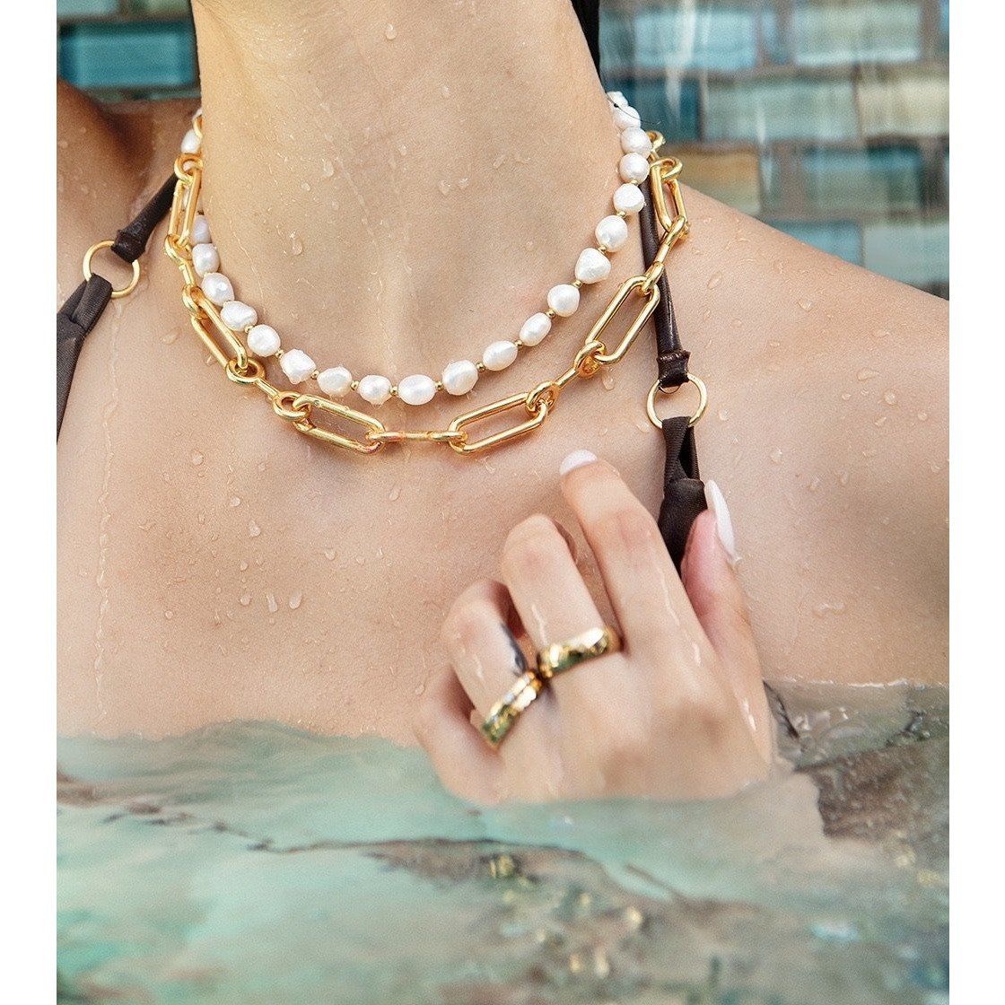 Gold and pearl necklace worn by a person with a blurred background