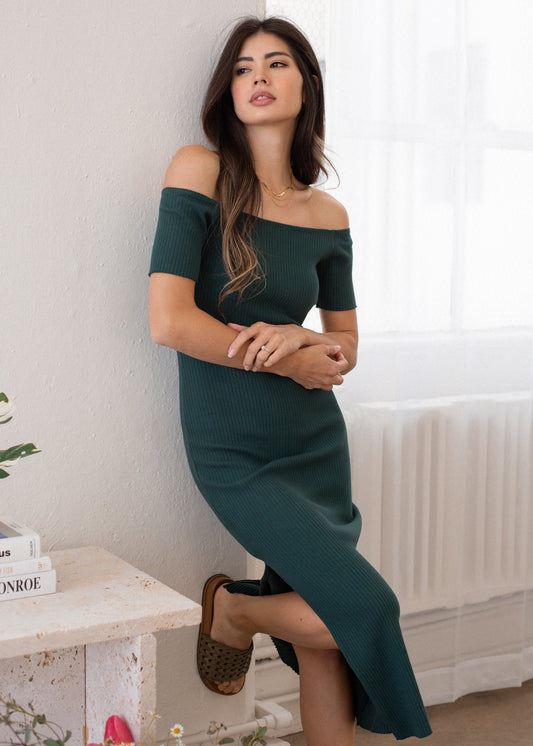 Woman wearing a green off-shoulder dress in a home setting