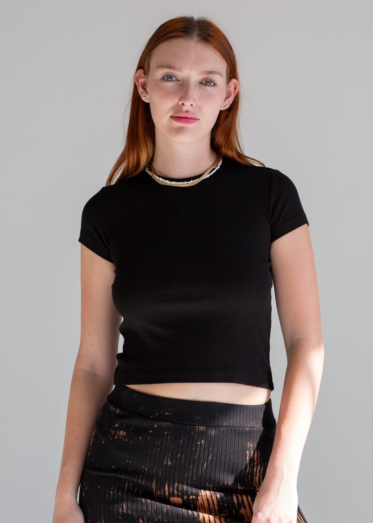 Person wearing a black crop top and dark pants against a gray background