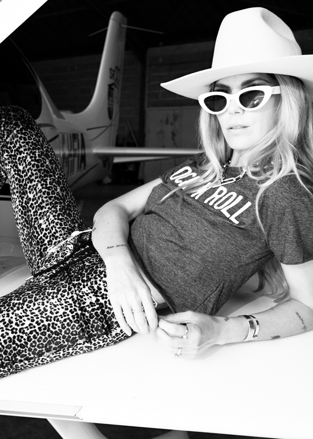 Person wearing a gray 'Rock & Roll' t-shirt, leopard print pants, and a white hat with sunglasses.