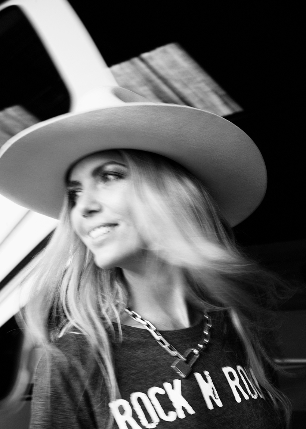 Black and white photo of a woman wearing a cowboy hat and 'Rock N Roll' shirt.