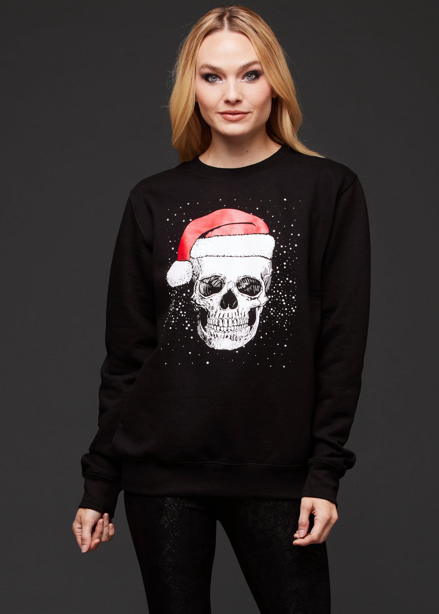 Person wearing a black sweatshirt with a skull design and Santa hat on a dark background
