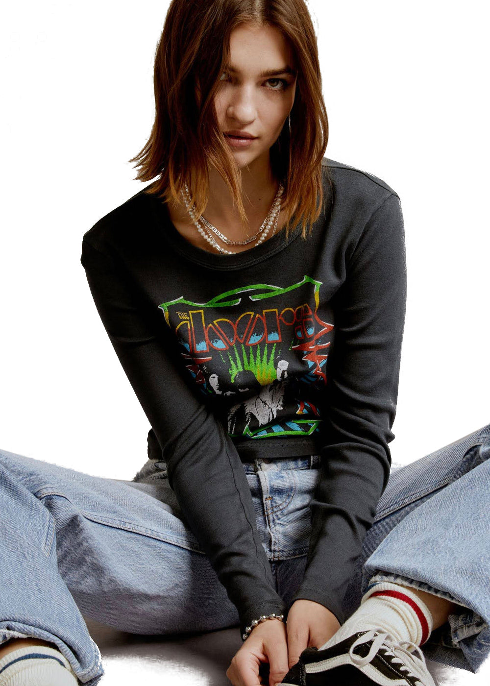 Person wearing a black graphic sweatshirt and jeans sitting on the floor.