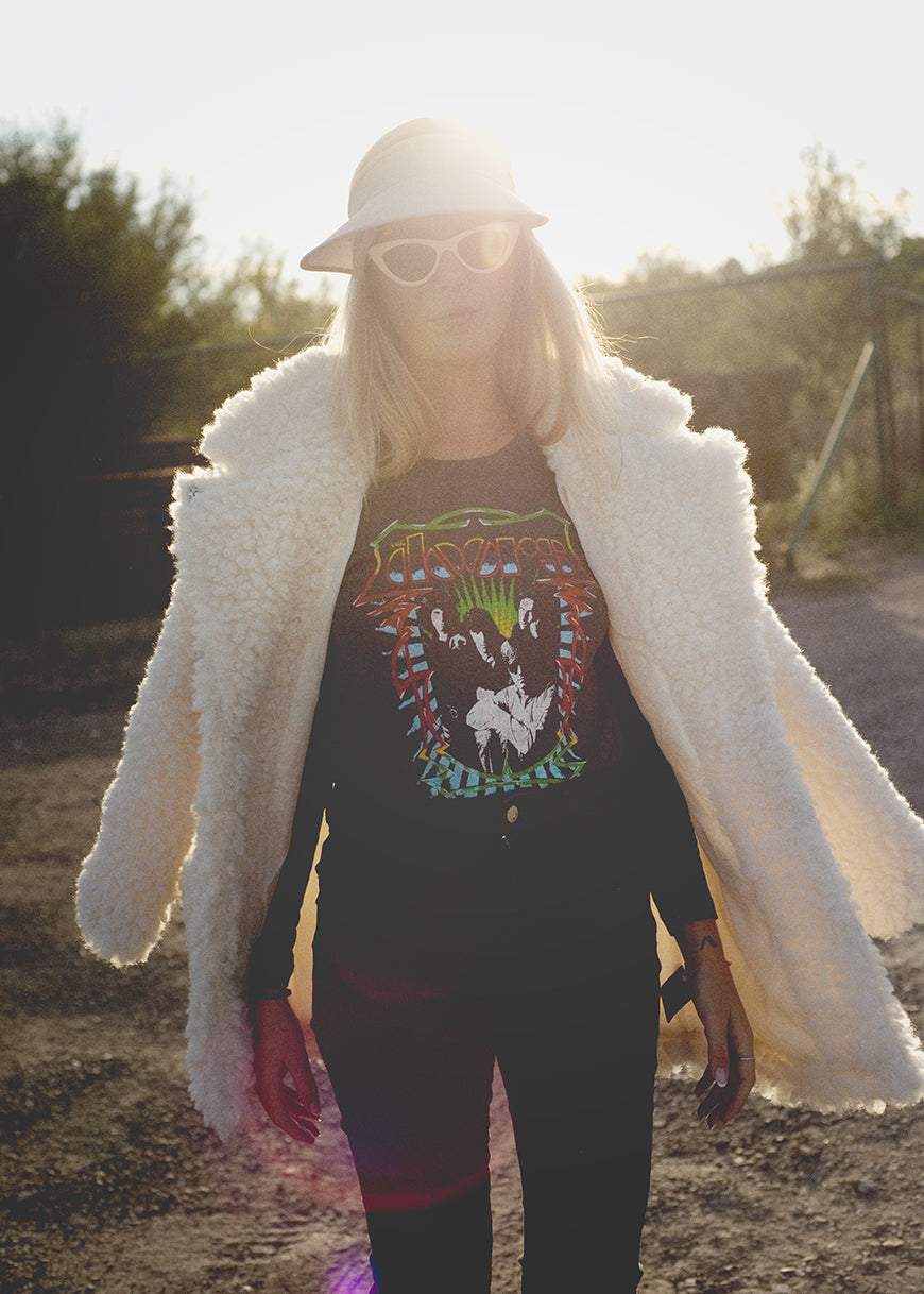 Person wearing a white coat and colorful graphic t-shirt outdoors
