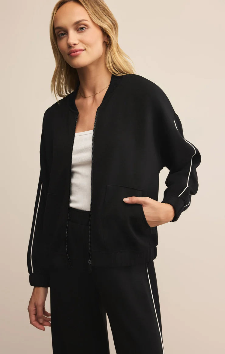 Woman wearing a black jacket with white accents on a beige background