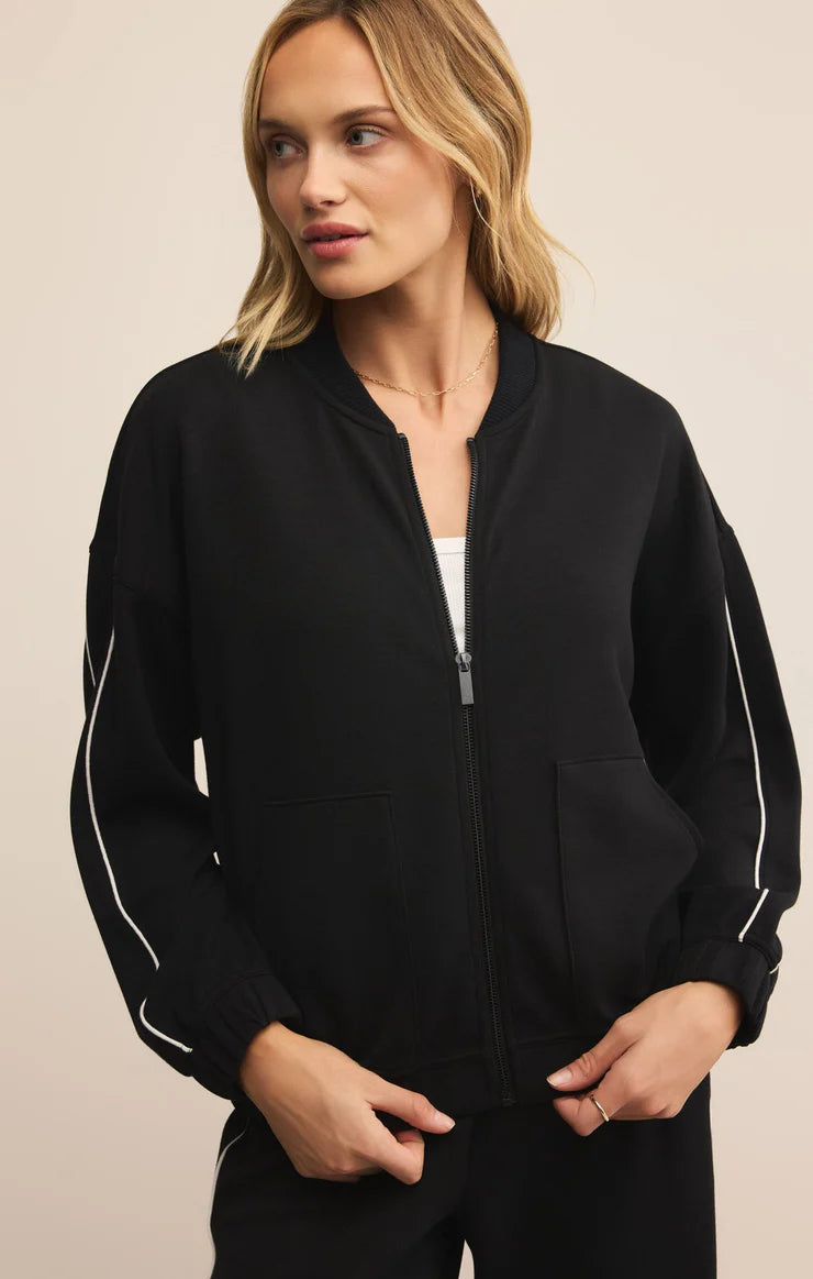 Woman wearing a black jacket with white accents on a beige background