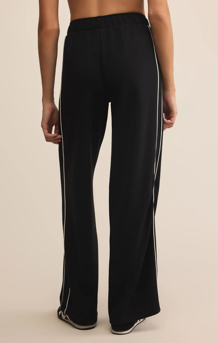 Black wide-leg pants with white stripes on a beige background
