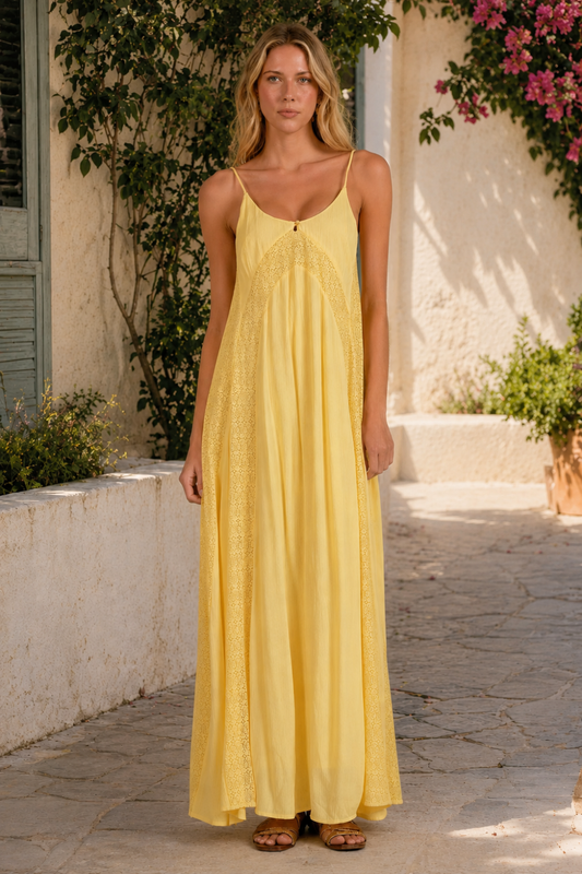 Woman wearing a yellow dress standing outdoors with plants and a building in the background