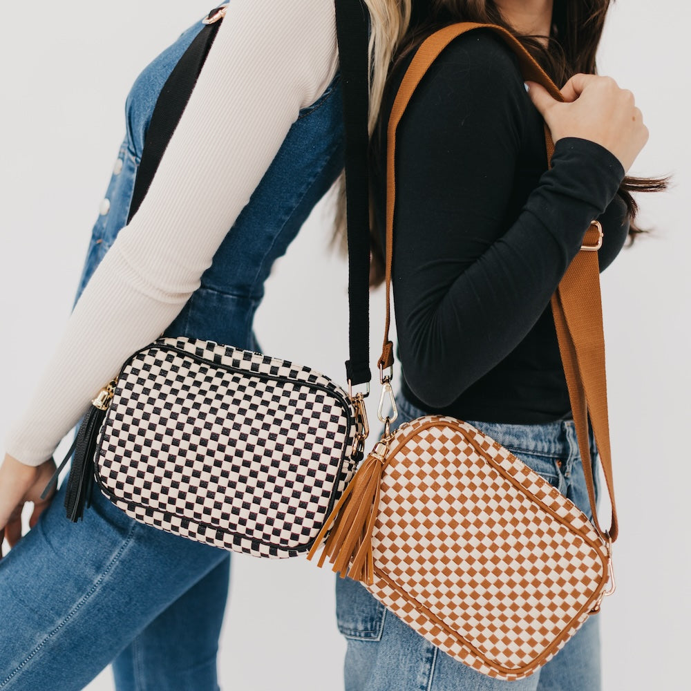 Two people holding checkered bags with a plain background