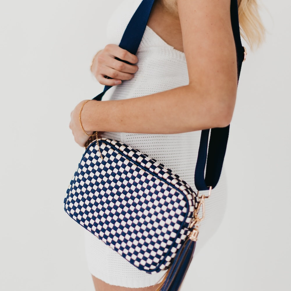 Navy and white checkered bag held by a person against a light background