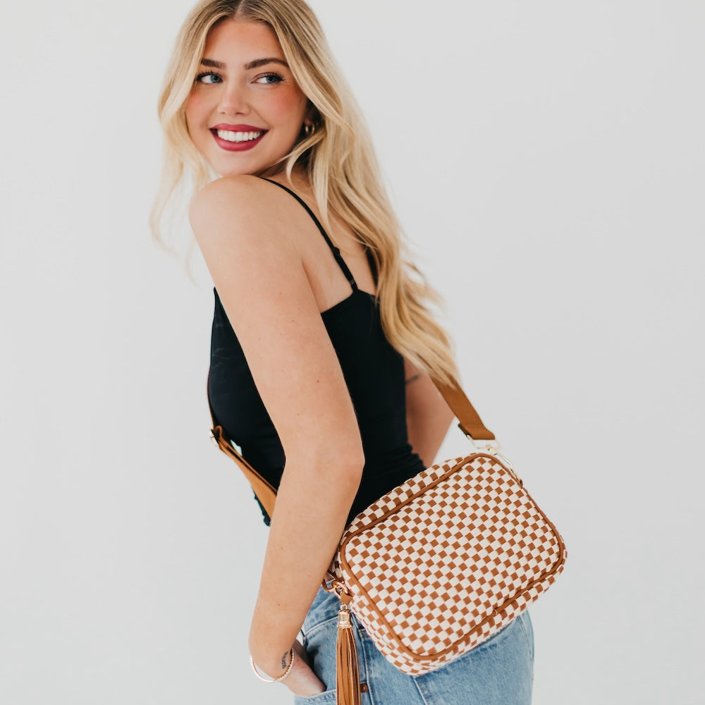 Woman holding a checkered bag against a plain background