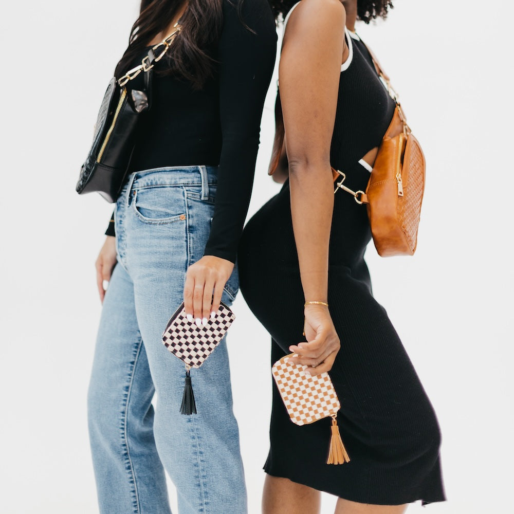 Two women holding small handbags with a plain background